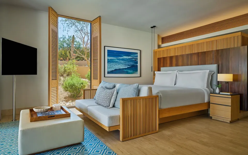 Bedroom of a Coastal View One Bedroom Suite at Montage Los Cabos with king bed, sofa, TV, and garden window.