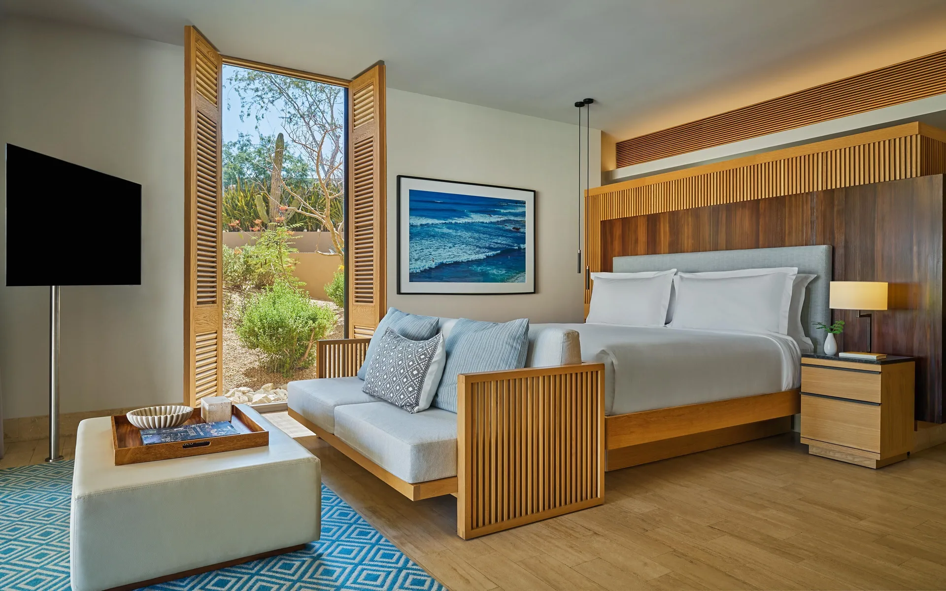 Bedroom of a Coastal View One Bedroom Suite at Montage Los Cabos with king bed, sofa, TV, and garden window.
