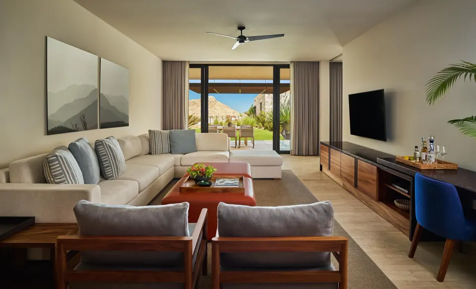 Living room of a Coastal View One Bedroom Suite at Montage Los Cabos with sofa, TV, desk, and patio view.