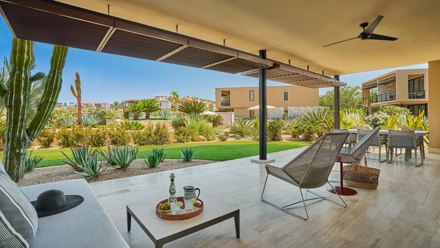 Covered terrace of a Coastal View One Bedroom Suite at Montage Los Cabos with lounge seating and desert landscaping.