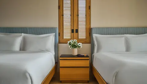 Ocean View Room with Pool at Montage Los Cabos with two beds, shared nightstand and shuttered window.