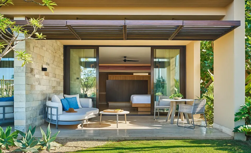 Ocean View Two Bedroom Suite patio with seating and bedroom beyond at Montage Los Cabos.