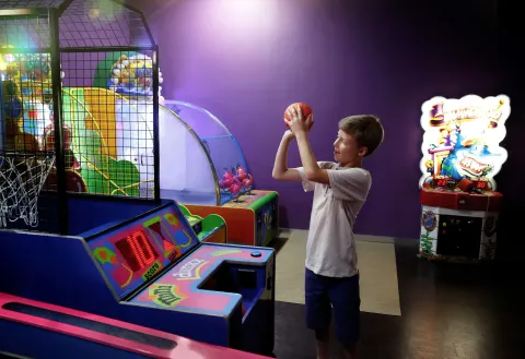 A child shoots a basketball arcade game in the play area at Moon Palace Cancun.