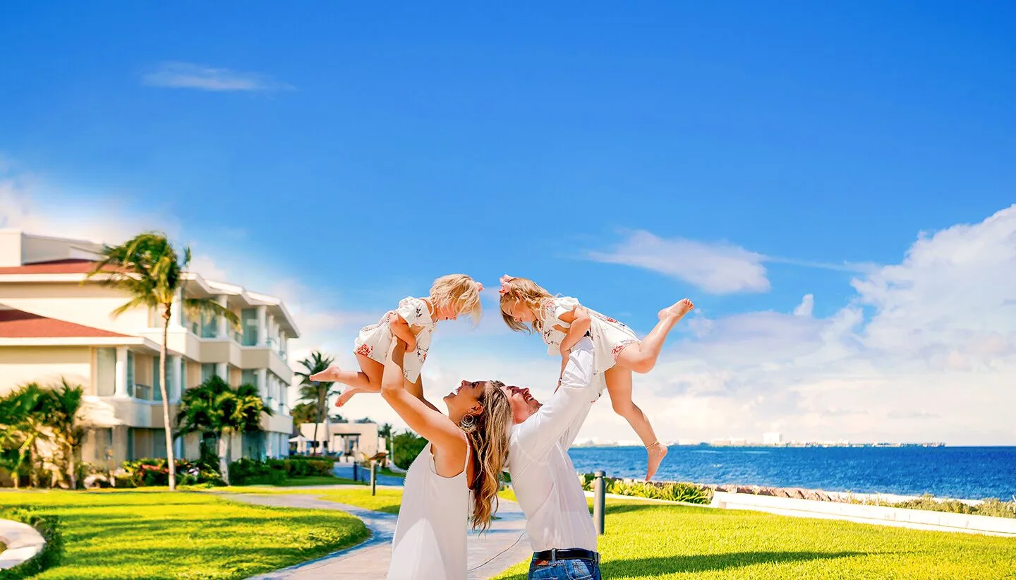 A family lifts two children on a seaside lawn at Moon Palace Cancun.