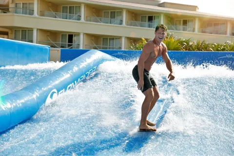Guest riding a FlowRider surf simulator at Moon Palace Cancun.
