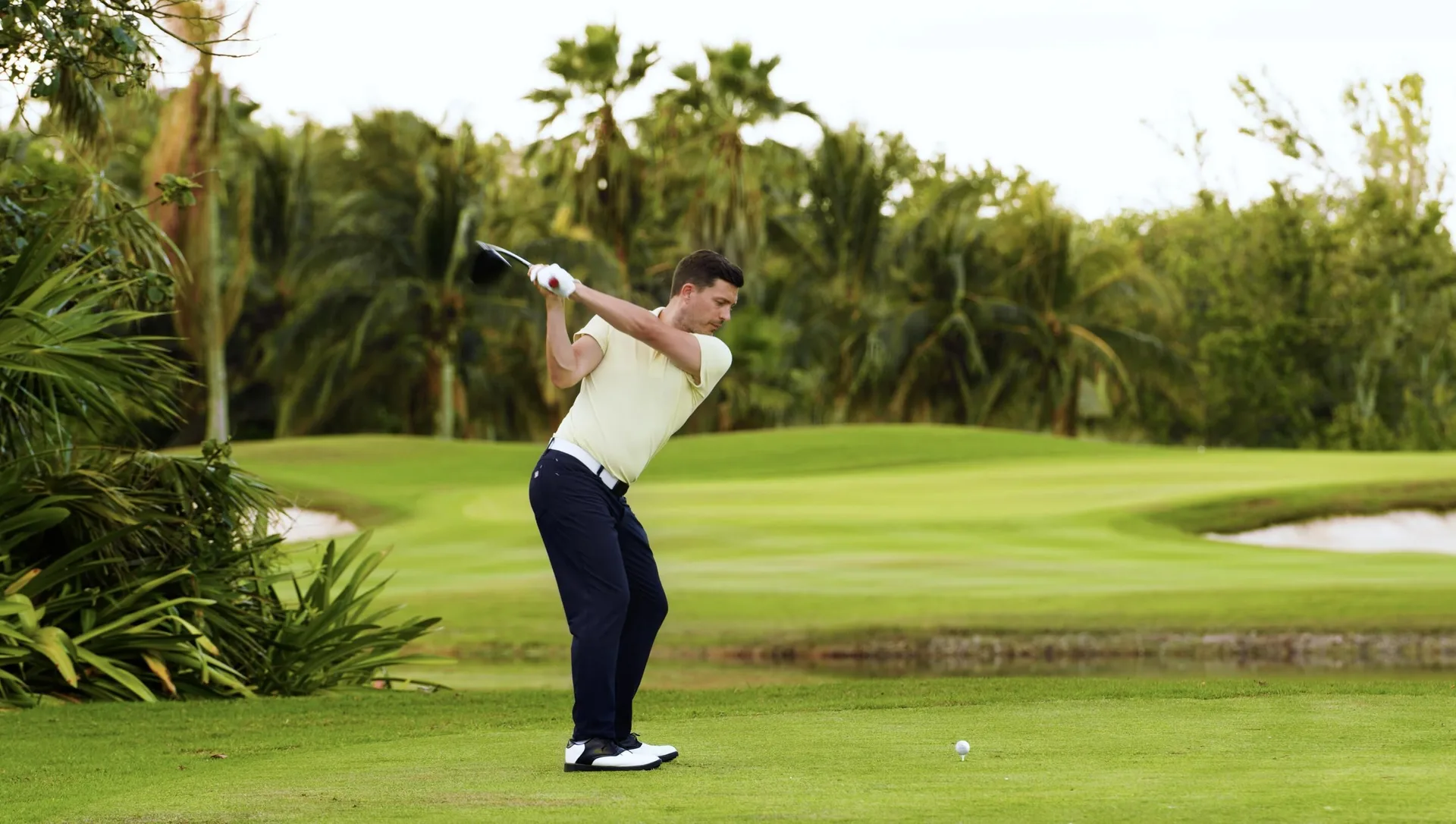 A golfer prepares to swing on a green fairway at Moon Palace Cancun.