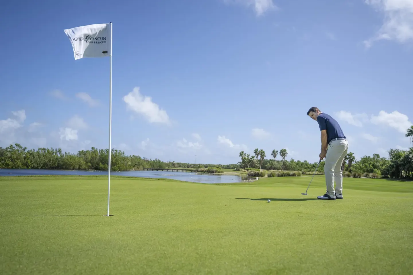 A golfer putts on a green beside water at Moon Palace Cancun.