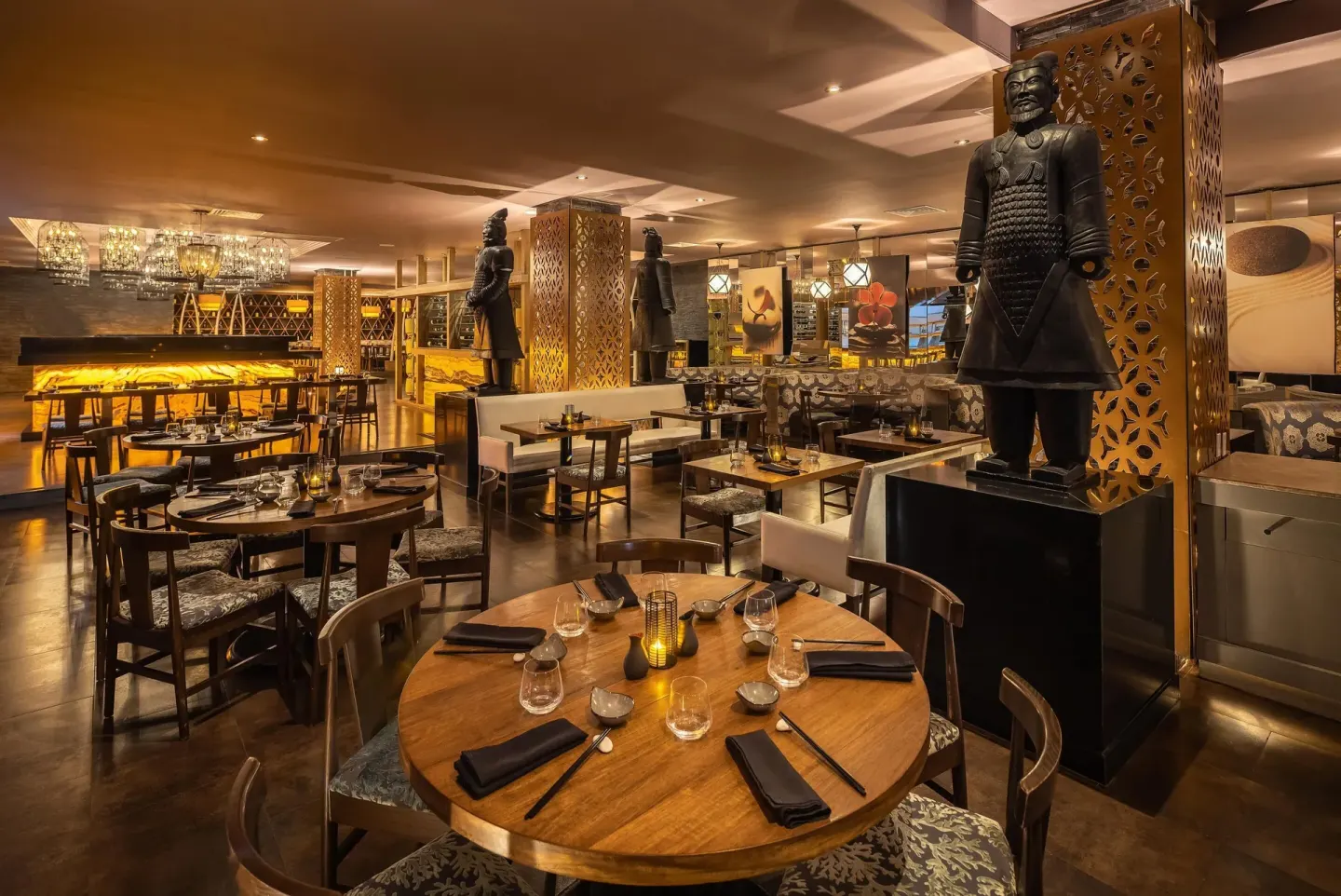 Pan-Asian style dining room with round tables and warrior statues at Moon Palace Cancun.