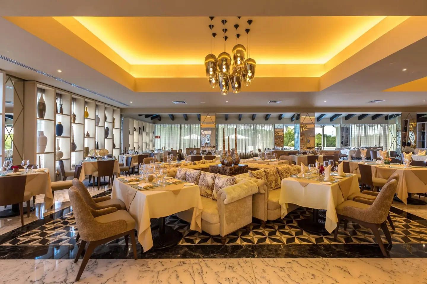 Restaurant dining room with central sofa seating and set tables at Moon Palace Cancun.