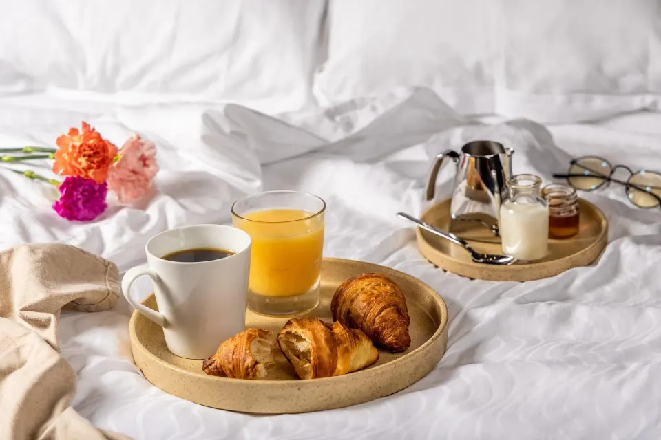 Breakfast tray with coffee, juice, and croissants on a bed at Moon Palace Cancun.