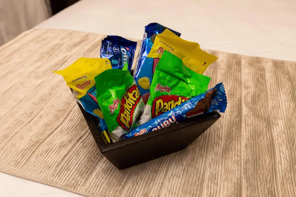 Basket of assorted packaged snacks on a bed at Moon Palace Cancun.