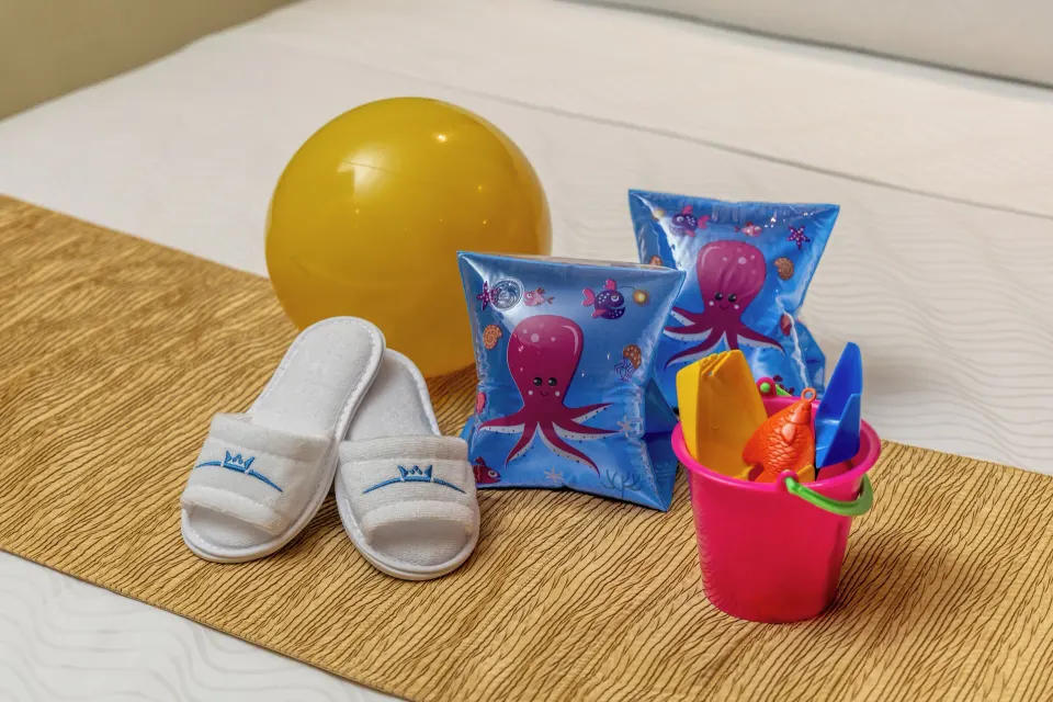 Children's pool toys and slippers on a guest room bed at Moon Palace Cancun.