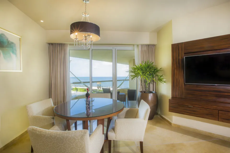 Superior Governor Suite dining table and TV beside ocean-facing balcony at Moon Palace Cancun.
