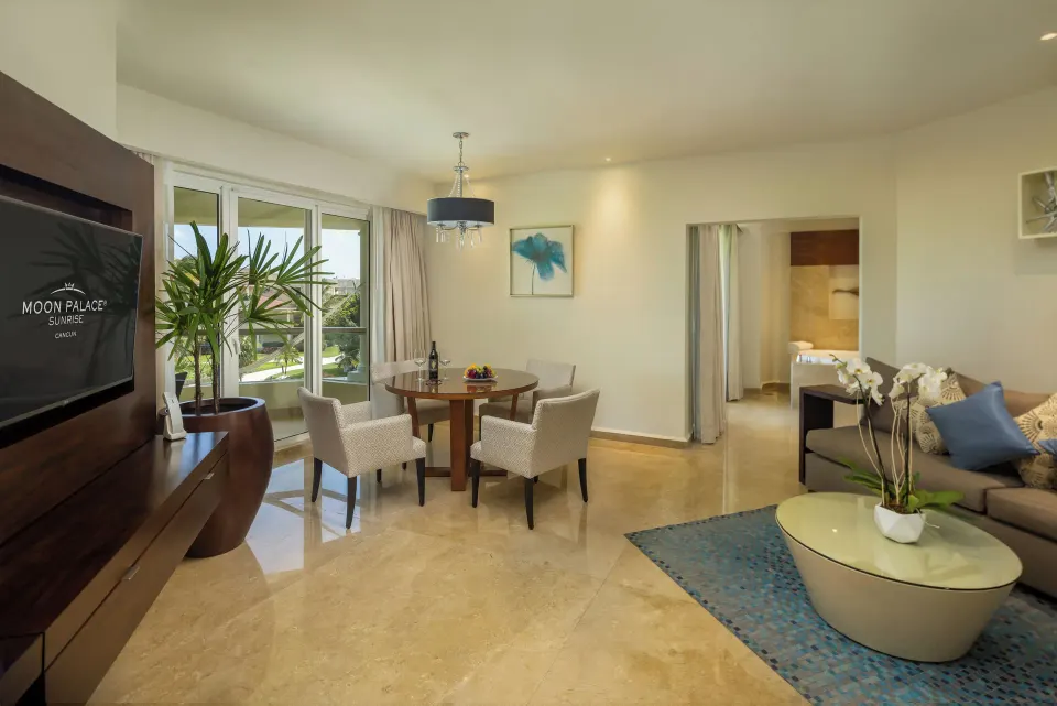 Superior Governor Suite lounge with sofa, dining table and balcony doors at Moon Palace Cancun.