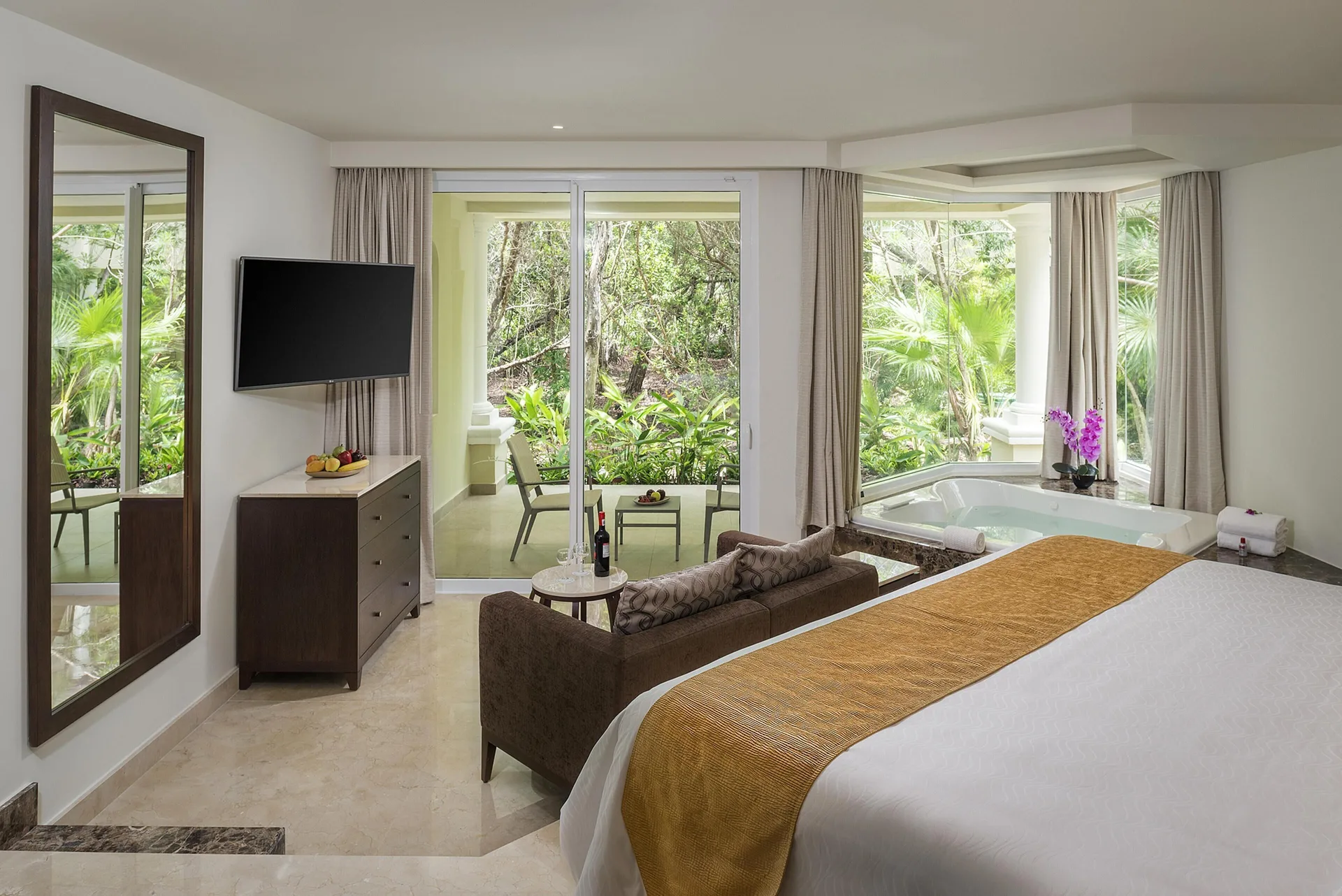 Superior Junior Suite king bed, soaking tub, balcony, and greenery at Moon Palace Cancun.