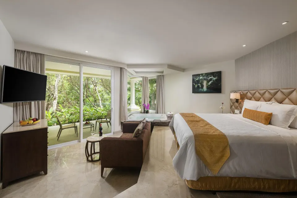 Superior Junior Suite king bed with sofa, tub, TV, and balcony at Moon Palace Cancun.