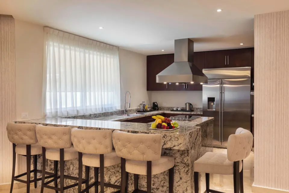 Villa kitchen with marble island, bar stools, and stainless refrigerator at Moon Palace Cancun.