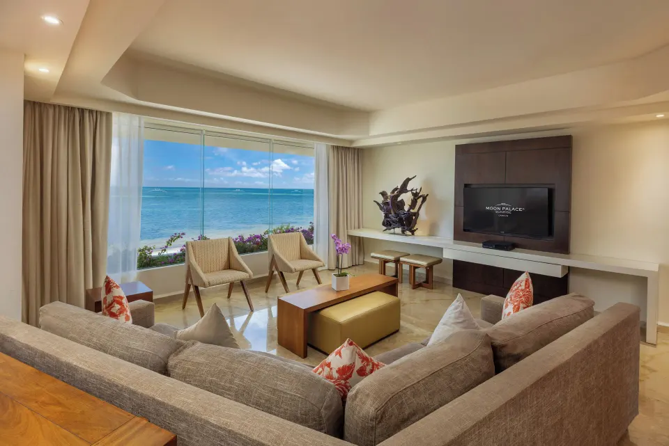 Villa living room with sofas, TV, and large ocean-facing windows at Moon Palace Cancun.