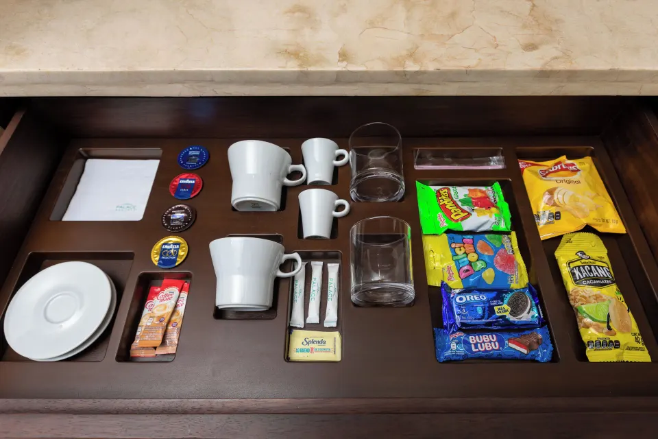 Coffee cups, pods, glasses, and snacks in a villa refreshment drawer at Moon Palace Cancun.