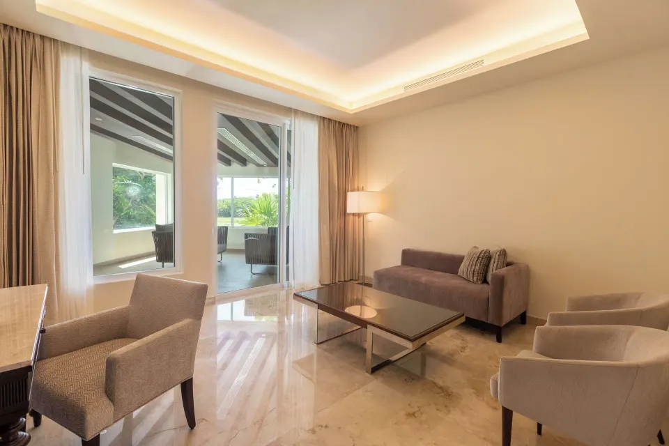 Villa sitting room with sofa, armchairs, coffee table, and terrace doors at Moon Palace Cancun.