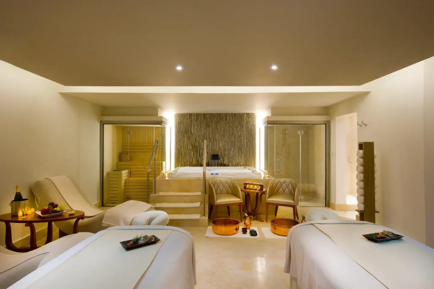 Spa treatment room with two massage tables, tub, sauna, and shower at Moon Palace Jamaica.