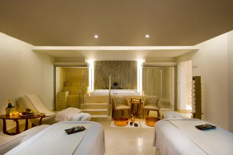 Spa treatment room with two massage tables, tub, sauna, and shower at Moon Palace Jamaica.