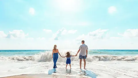 A family holds hands in the surf on the beach at Moon Palace Jamaica.