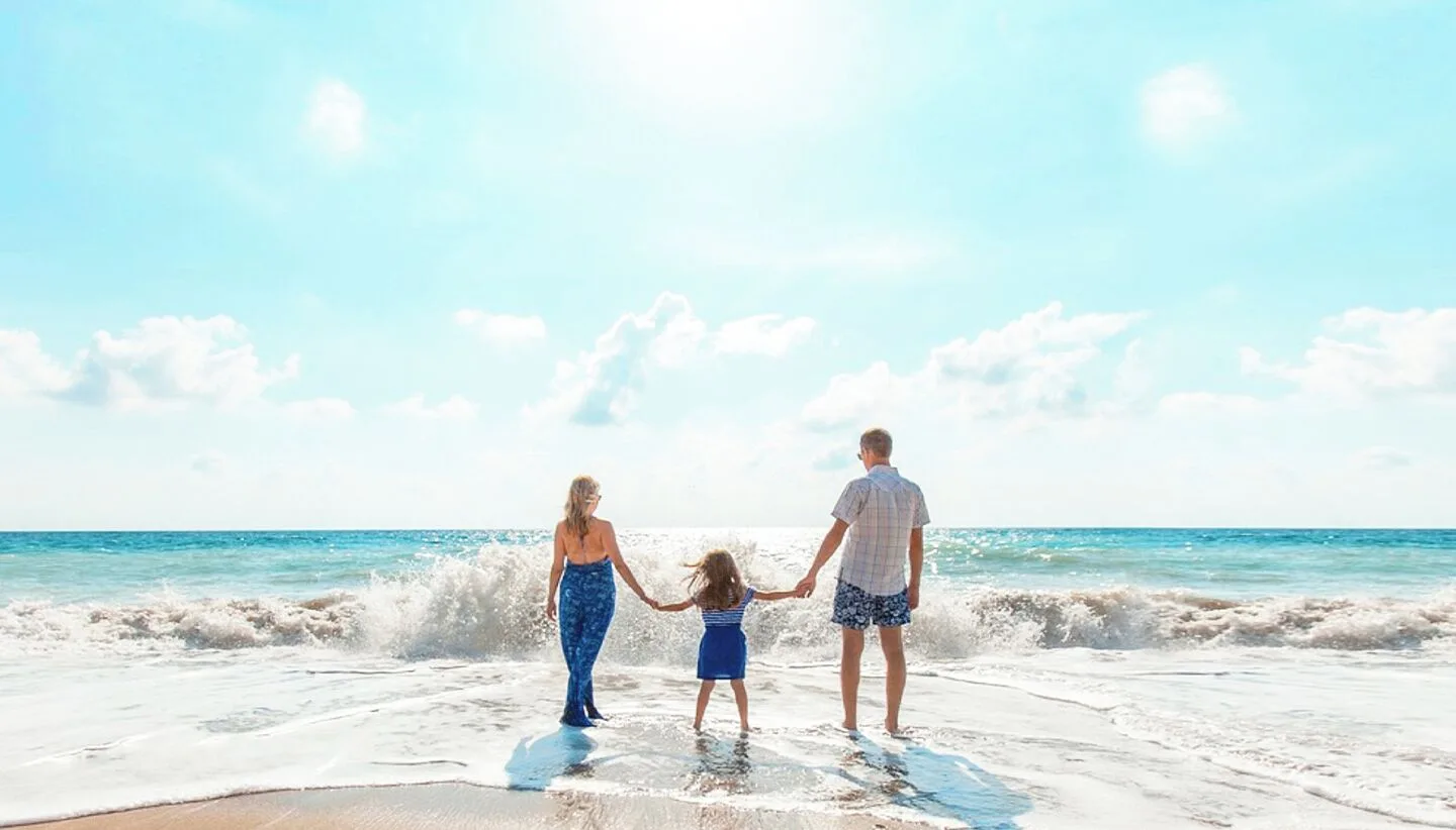 A family holds hands in the surf on the beach at Moon Palace Jamaica.