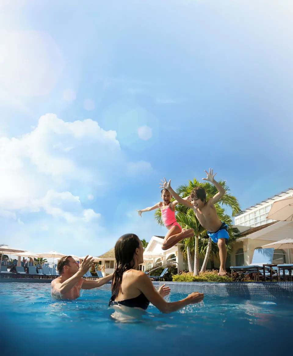 Children jump into a resort pool toward waiting adults at Moon Palace Jamaica.