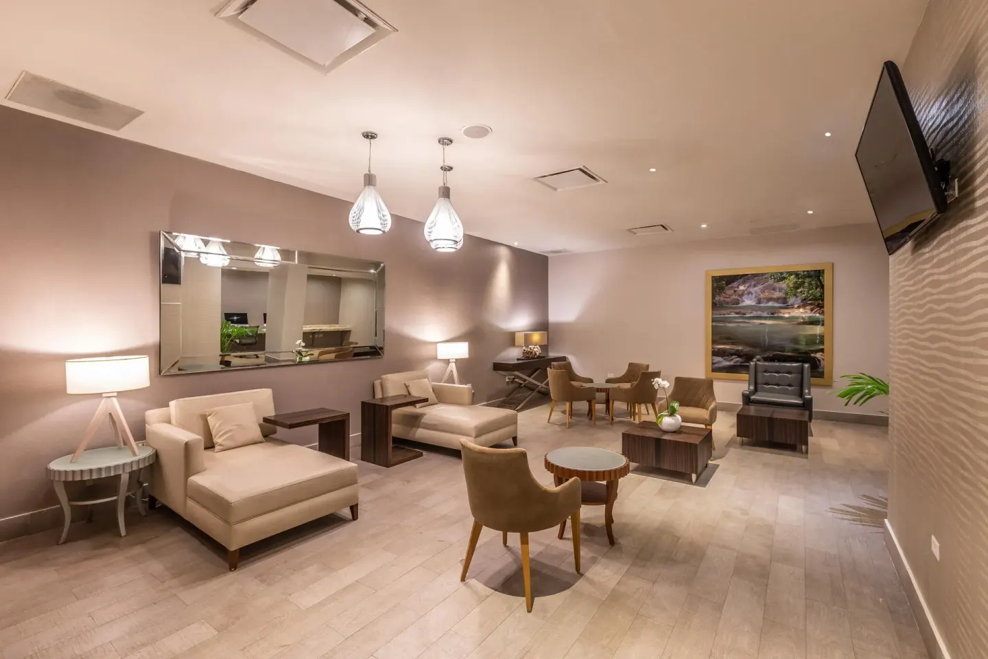 A lounge with chaise seating, tables, lamps, and wall art at Moon Palace Jamaica.