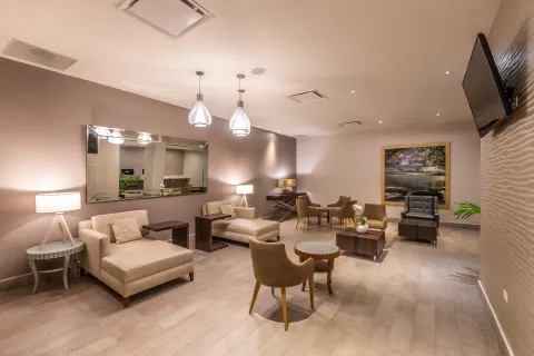 A lounge with chaise seating, tables, lamps, and wall art at Moon Palace Jamaica.