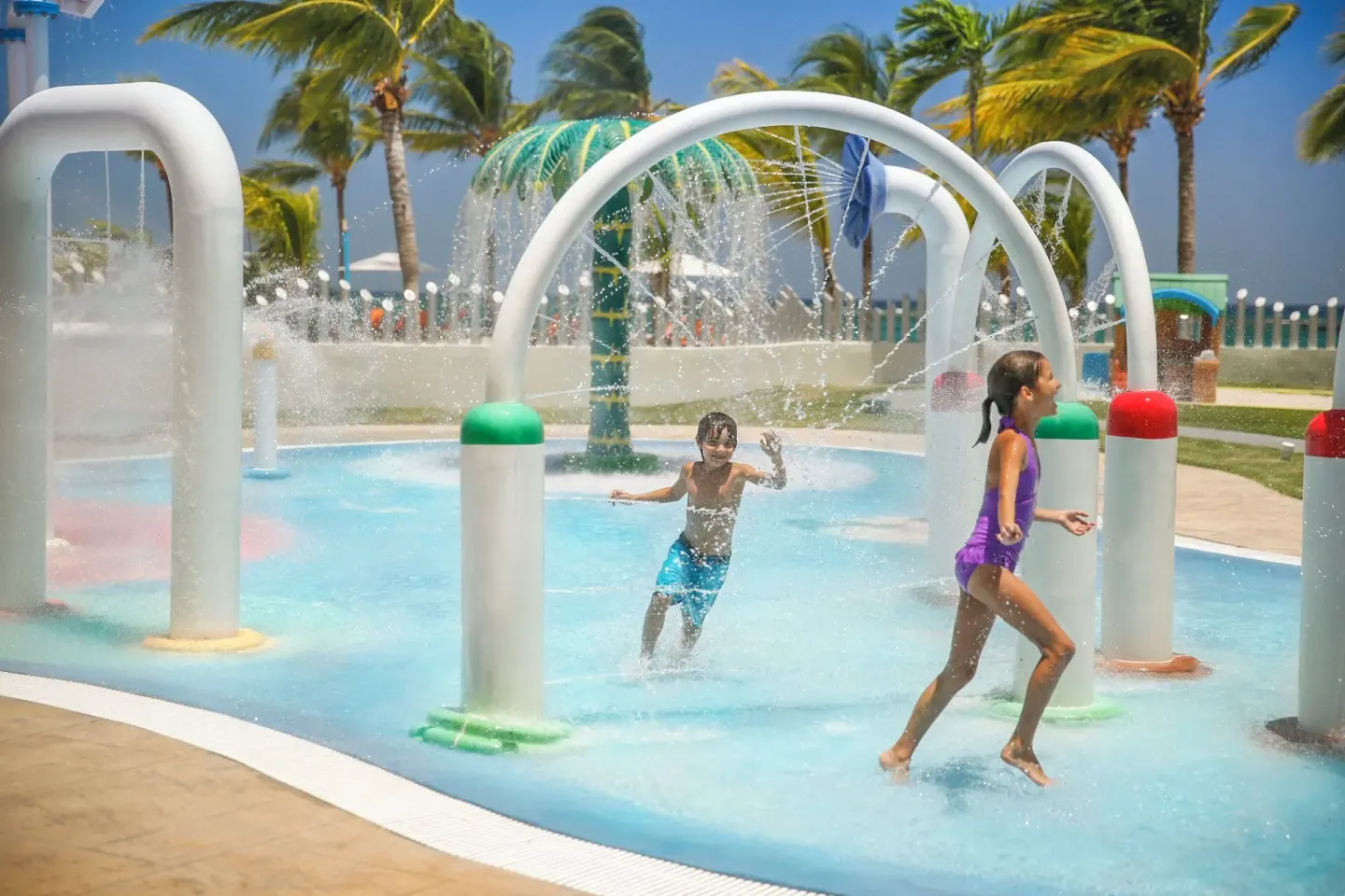 Children run through spray arches in the water play area at Moon Palace Jamaica.