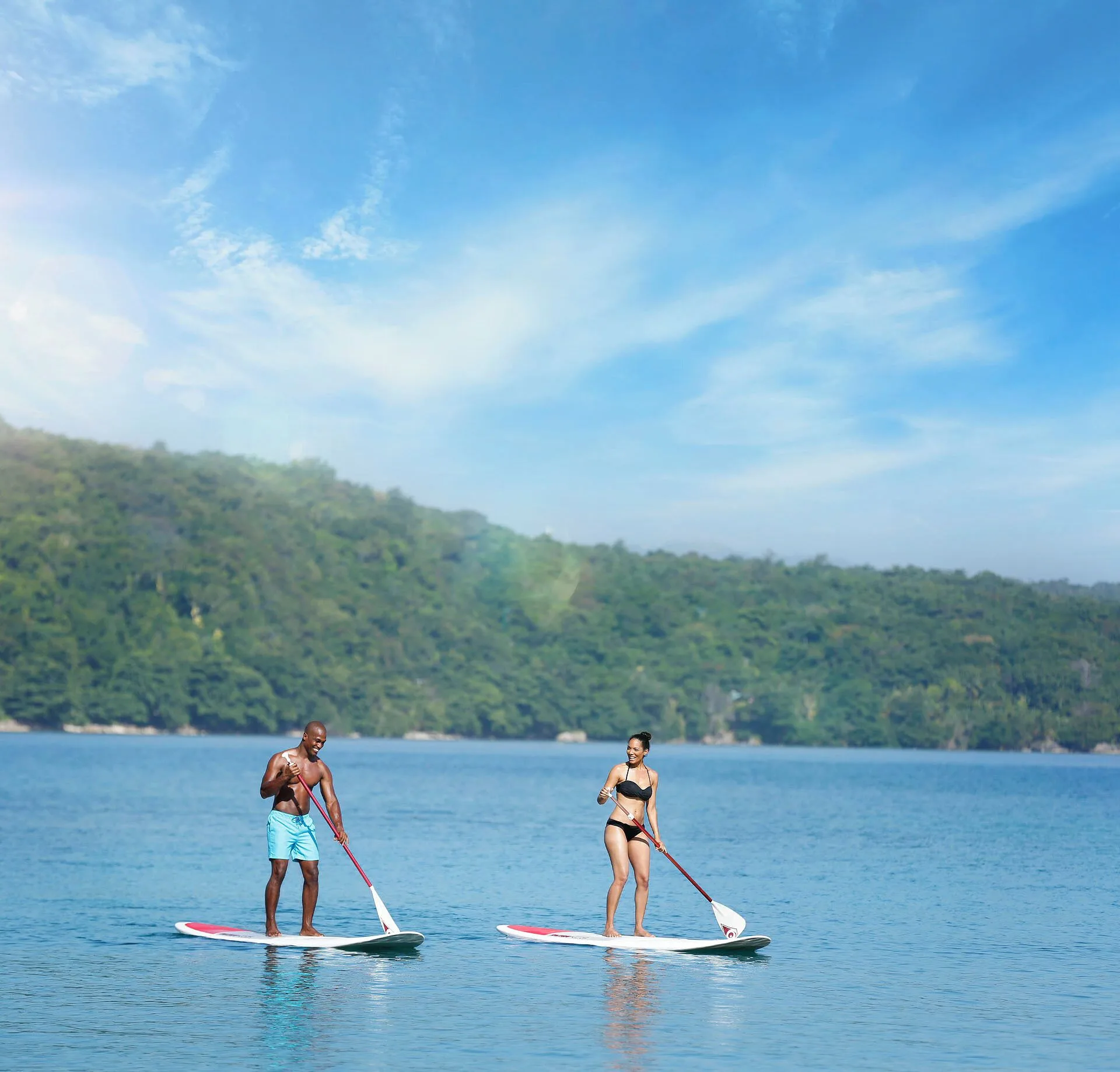 Two guests paddleboard on calm blue water near Moon Palace Jamaica.