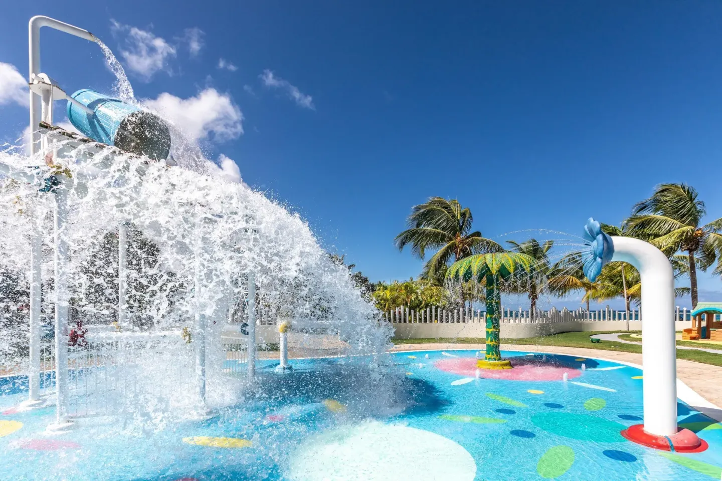 A tipping bucket pours water over a colorful splash pad at Moon Palace Jamaica.