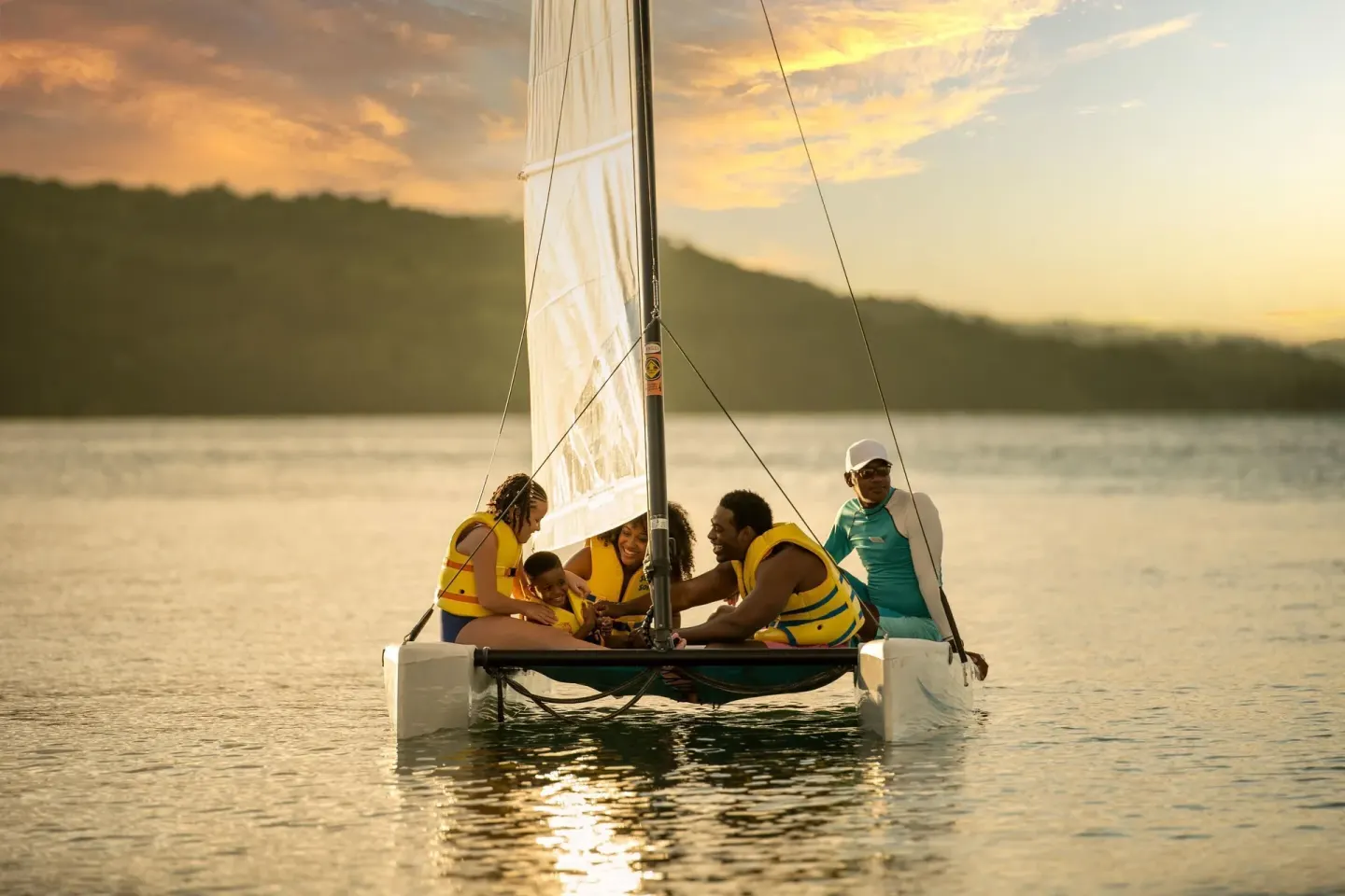 Family sailing on a small catamaran at sunset at Moon Palace Jamaica.