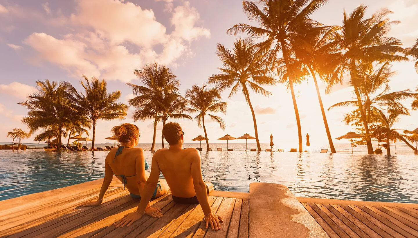 Guests sit by the palm-lined pool at sunset at Moon Palace Jamaica.