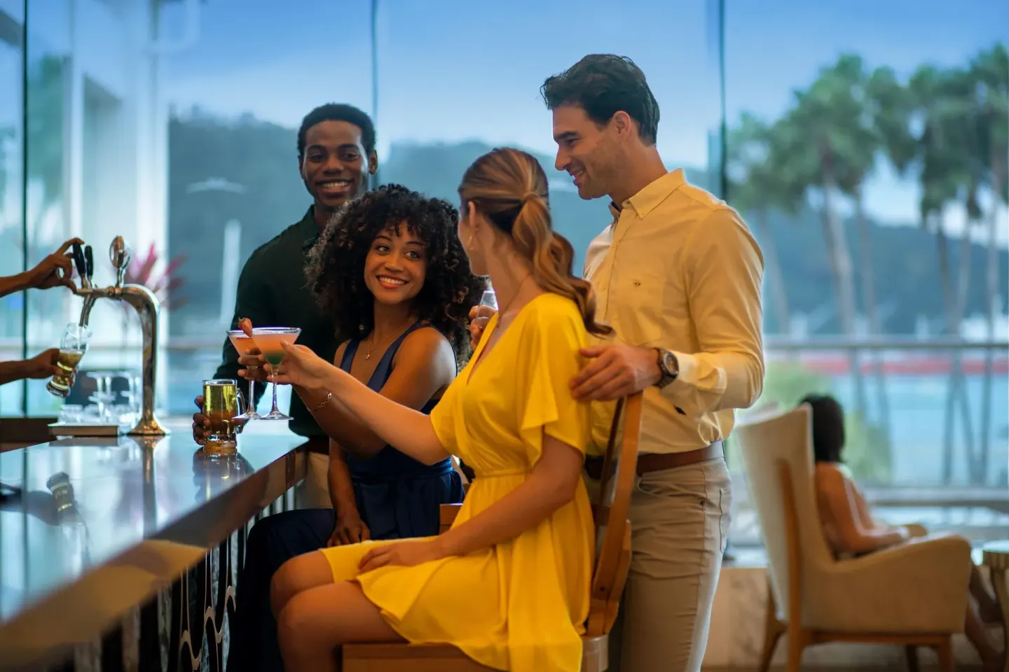 Guests enjoy cocktails at a bar with large windows at Moon Palace Jamaica.