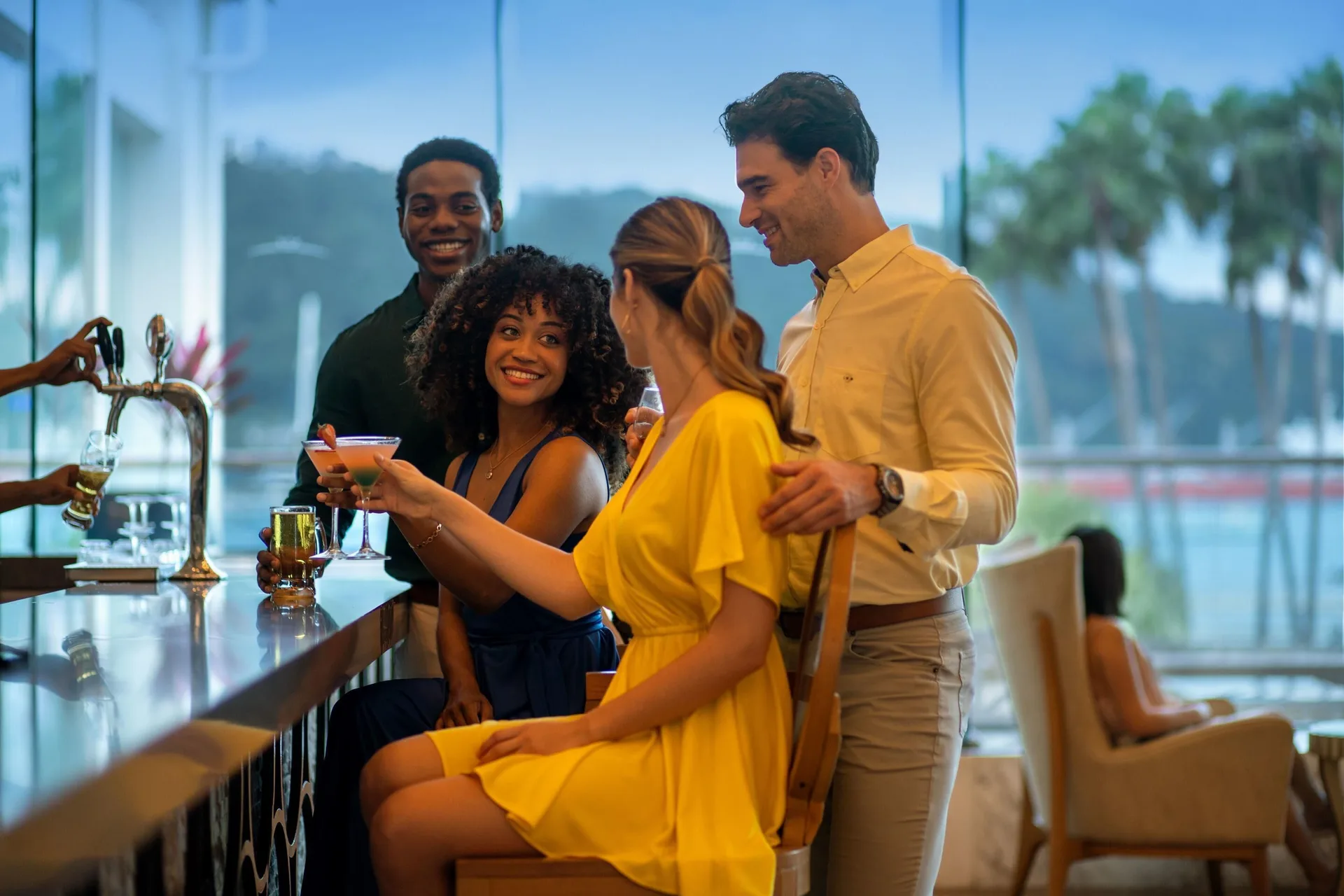 Guests enjoy cocktails at a bar with large windows at Moon Palace Jamaica.