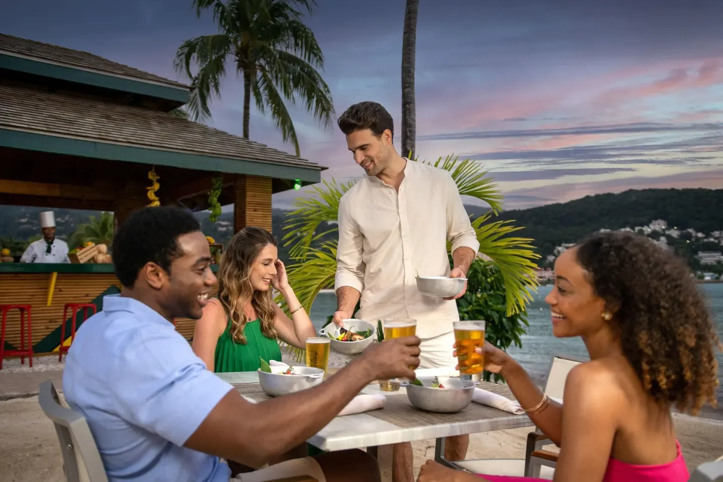 Guests toast drinks at an outdoor waterfront table at Moon Palace Jamaica.