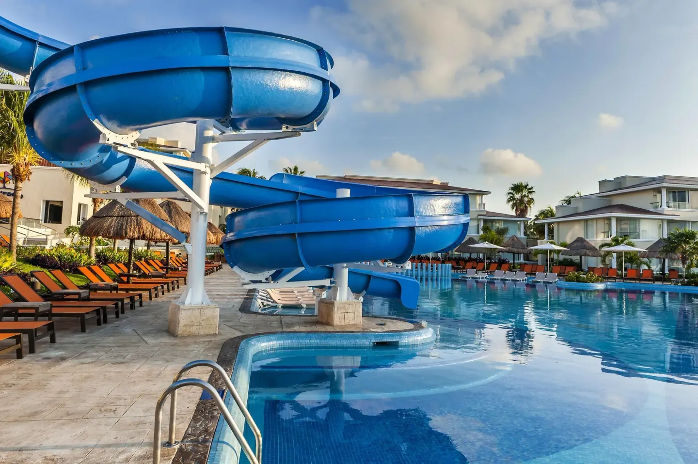 Close view of blue waterslides beside a pool and lounge chairs at Moon Palace Nizuc.
