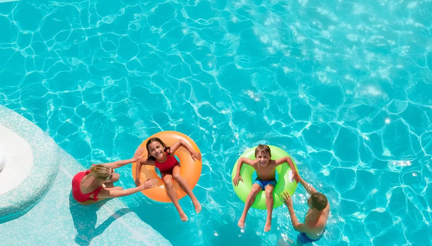 Children floating in colorful tubes with adults in a pool at Moon Palace Nizuc.