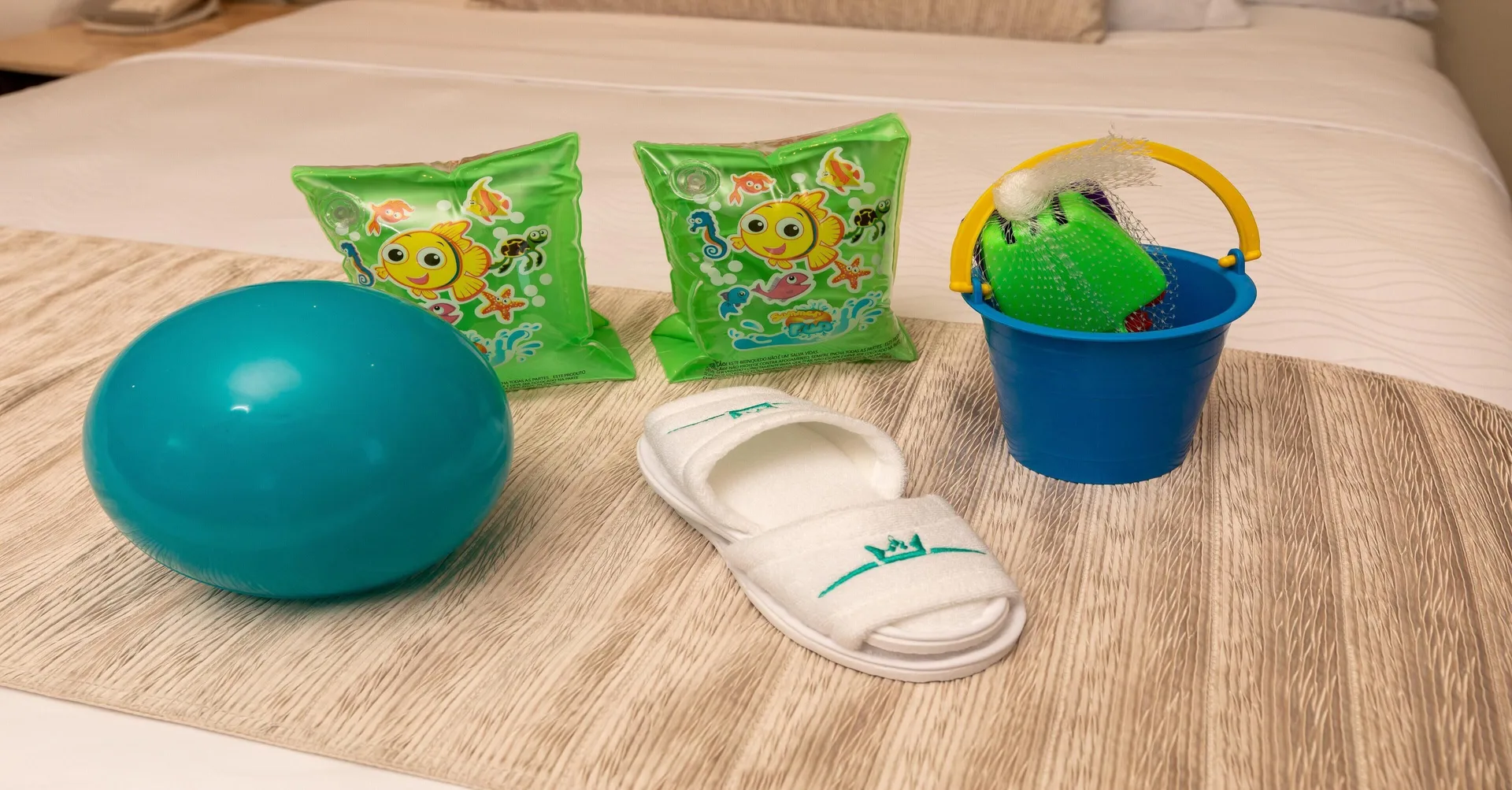 Children's pool toys, floaties, bucket, and slippers on a bed at Moon Palace Nizuc.