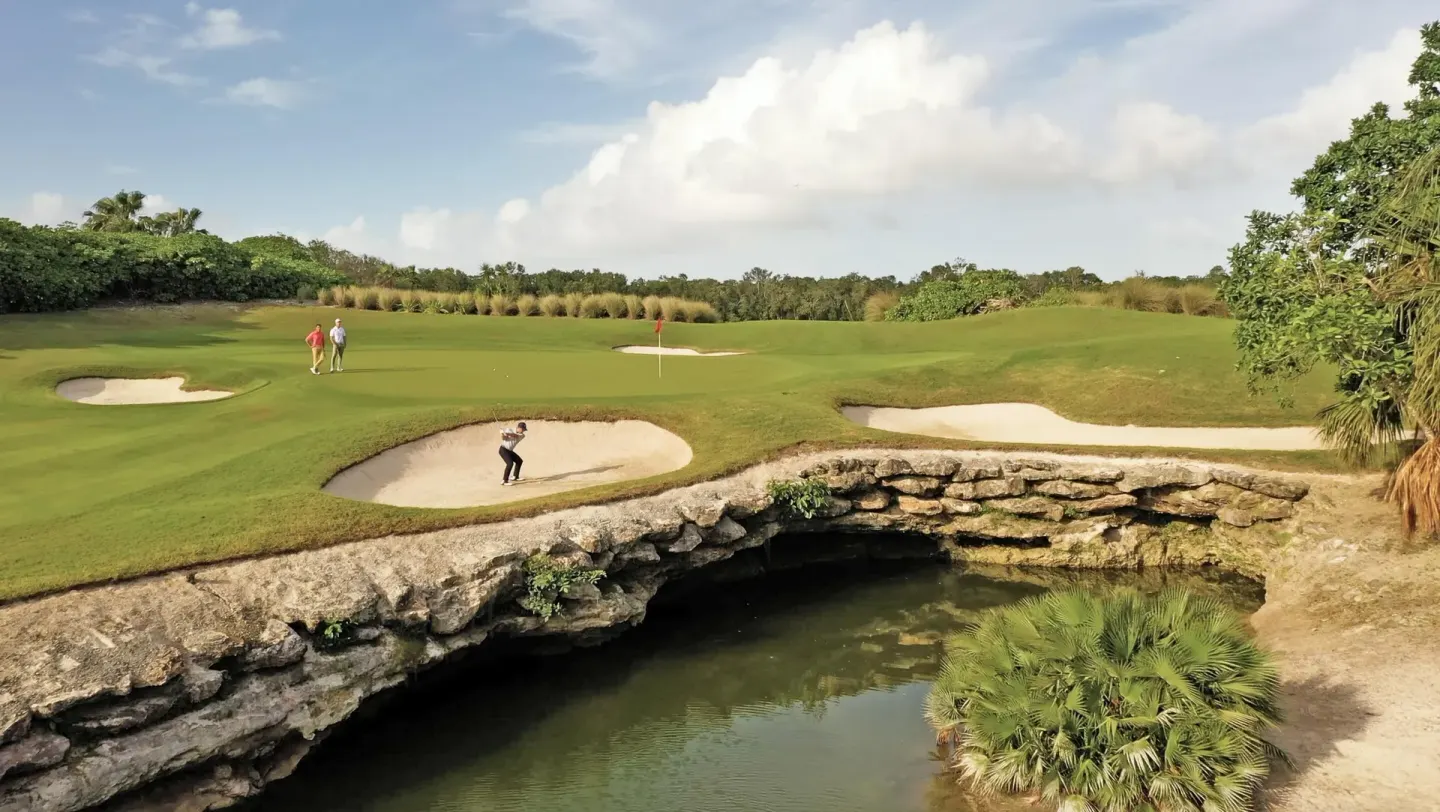 Golf green with sand bunkers and rocky water feature at Moon Palace Nizuc.