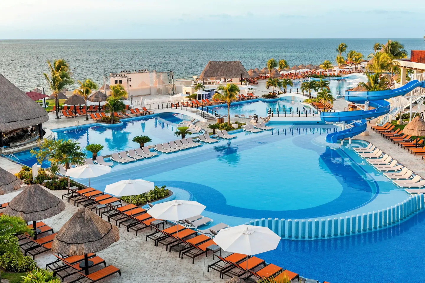 Aerial view of pools, loungers, umbrellas, and blue waterslide at Moon Palace Nizuc.