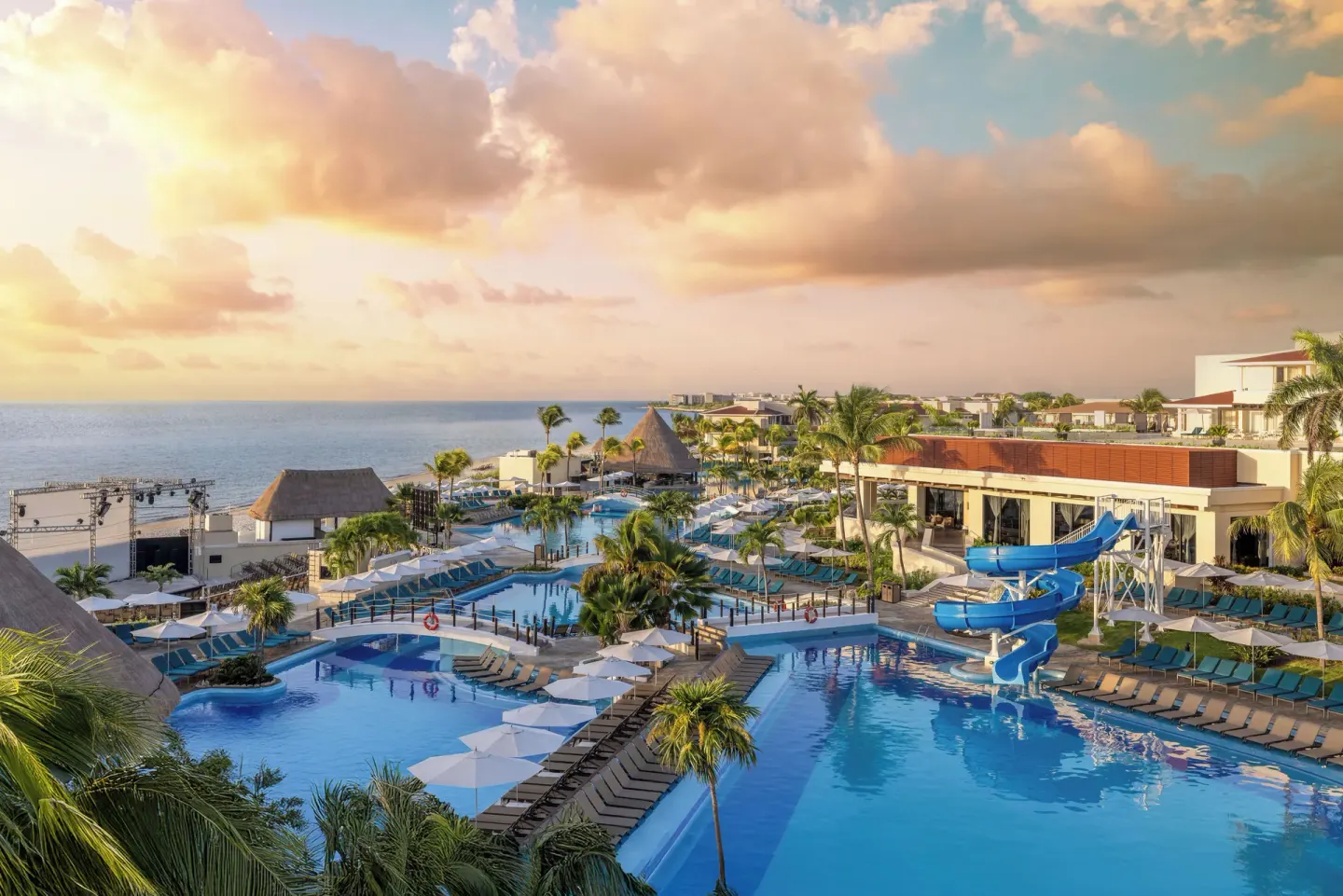 Sunset view over pools, palms, loungers, and waterslides at Moon Palace Nizuc.