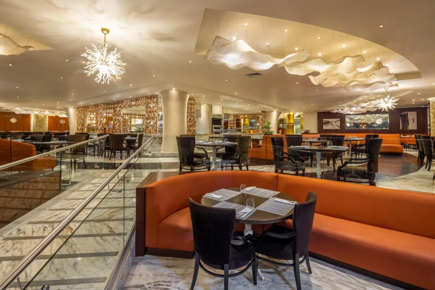 Large dining room with orange banquettes and sculptural lights at Moon Palace Nizuc.