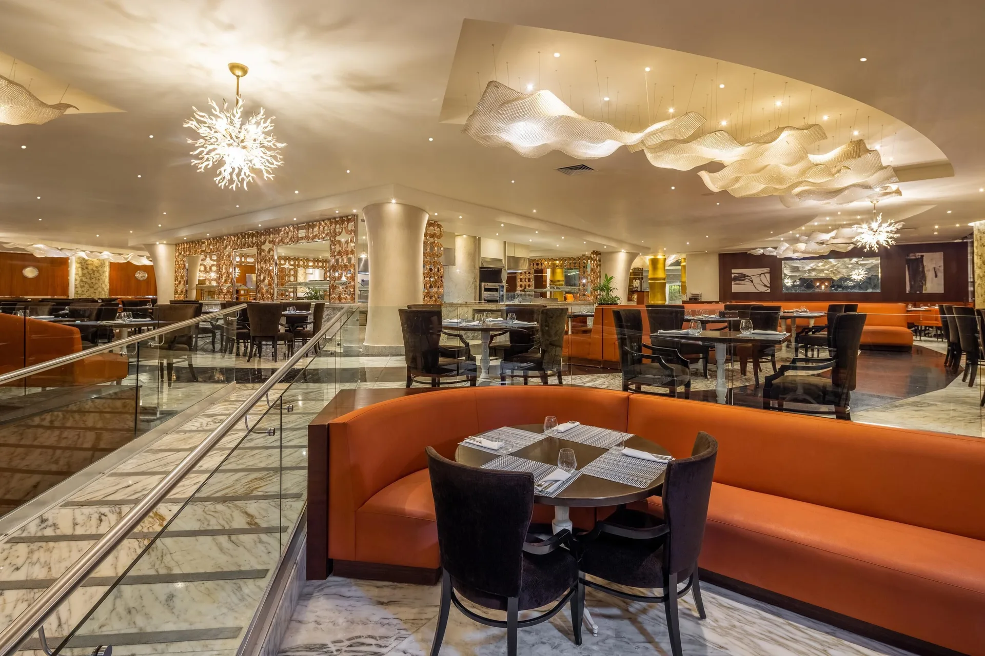 Large dining room with orange banquettes and sculptural lights at Moon Palace Nizuc.