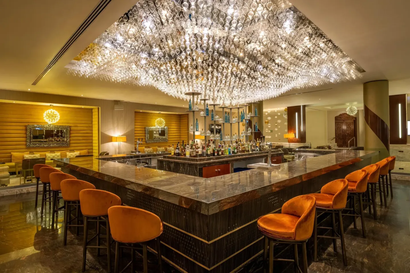 Elegant lobby bar with crystal ceiling lights and orange stools at Moon Palace Nizuc.