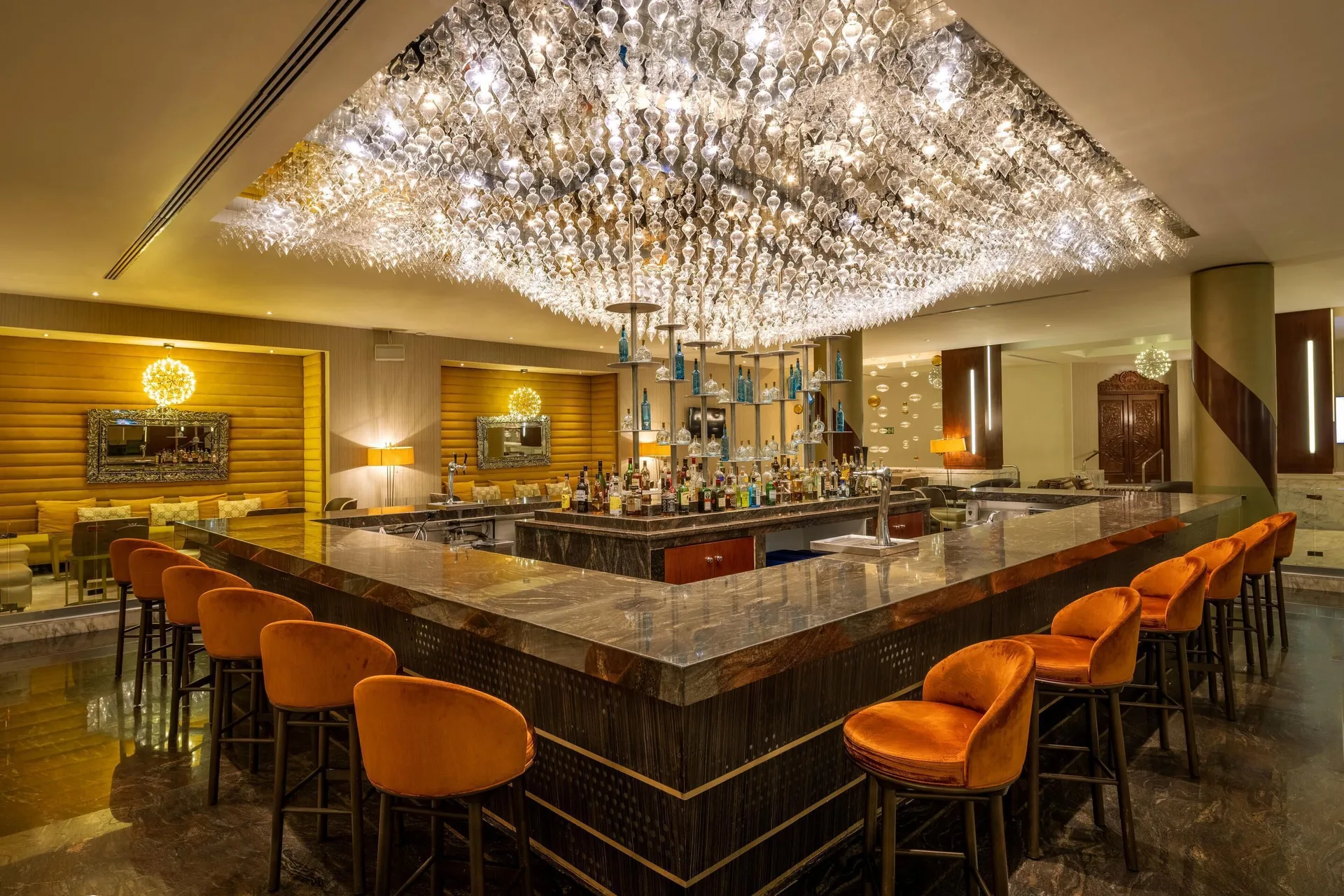 Elegant lobby bar with crystal ceiling lights and orange stools at Moon Palace Nizuc.