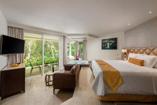 King-bed superior junior suite with sofa and terrace doors at Moon Palace Nizuc.